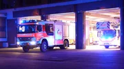 Fire truck and turntable ladder from Aschaffenburg leave the hall at night.