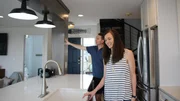 The kitchen in Sandy Lookout has beautiful new stainless steel appliances and light fixtures, which contributors Jon Mason (L) and Lauren Mason (R) take a look out while touring the home as seen on HGTV's Beachfront Bargain Hunt.
