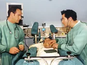 Dr. Kreutzer (Johannes Steck, links) und Dr. Brentano (Thomas Koch, rechts) treffen alle Vorbereitungen, um ihren Chefarzt Dr. Heilmann (Thomas Rühmann) wieder aus dem Koma zu holen. Doch dann kommt etwas unerwartetes dazwischen.