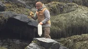 Bill McConnell on a rocky shore with a buoy and work gloves on Maine.
