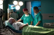 Dr. Kaminski (Udo Schenk, re.) und Dr. Globisch (Andrea Kathrin Loewig) wollen Susann Mess (Catherine Bode, liegend) operieren. Doch das ist in ihrem Zustand fast unmöglich, da sie einem Weinkrampf nahe ist.
