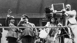 Leni Riefenstahl bei der Kamera, w&auml;hrend der Dreharbeiten von &bdquo;Olympia&ldquo; mit Joseph Goebbels und Hermann G&ouml;ring auf der Trib&uuml;ne (1936) (aus dem Nachlass).