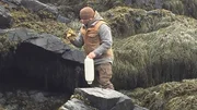 Bill McConnell on a rocky shore with a buoy and work gloves on Maine.