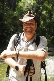 Josh Gates posiert in einem rei&szlig;enden Fluss.