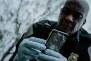 Rekonstruktion eines Dramas: Männlicher Polizist hält ein zertrümmertes Telefon. Rekonstruktion eines Dramas: Männlicher Polizist hält ein zertrümmertes Telefon.