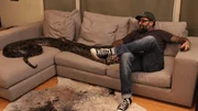 Host Antonio Ballatore sits on the couch with the large python.