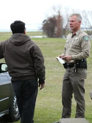 Warden Benny Richards holding the fisherman&rsquo;s license.