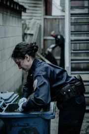 Polizistin durchsucht Mülltonnen. Polizistin durchsucht Mülltonnen.