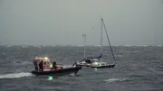 Segler im Sturm. Seenotretter versucht vom Tochterboot auf Havaristen überzusteigen. Segler im Sturm. Seenotretter versucht vom Tochterboot auf Havaristen überzusteigen.