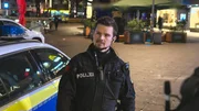 Lukas Weide-Hannemann standing next to a police car looking to the left