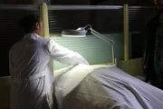 The medical examiner covering victims body with a sheet.