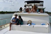 Tiffany Franco feeding Rocky Russo fruit on the yacht while Mei Tang, Cole Anderson, Chad Gloer, Kassidy Gillis, Tim Malcolm and Rob Warne sit at the top chatting