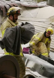 Feuerwehrleute helfen den benommenen Passagieren in Sicherheit.