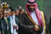Mohammed Bin Salman l&auml;uft mit saudischer Kopfbedeckung an einer Reihe von Menschen vorbei.