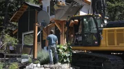 A wide shot of the Hood homestead with a build crew and excavator in front of the home. A wide shot of the Hood homestead with a build crew and excavator in front of the home.