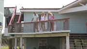 Splash to the Future features multiple decks for optimal beach views, which real estate agent Lisa Gregory (R) shows off to contributors Jason Clark (L) and Jennifer Clark (C) as seen on HGTV's Beachfront Bargain Hunt.