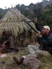 Feuer brennt, w&auml;hrend Josh James (l.) Grady Powell (r.) beim Trinken aus dem Reifen zusieht.