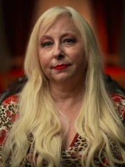 Die befragte Person, Rochelle Herman, sitzt auf einem Stuhl und schaut in die Kamera. Mittelaufnahme.