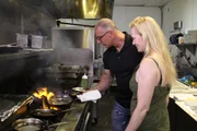 Host Robert Irvine shows Julie a few new tricks in the kitchen, as seen on Food Network's Restaurant: Impossible, Season 12.