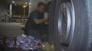 Ein Grenzbeamter entfernt versteckte Drogen aus einem Lastwagen.
