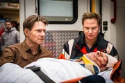 Dr. Haase (Fabian Harloff, r.) kümmert sich um seinen Patienten Werner Karger (André Eisermann, liegend), der mit seinem Wagen auf ein parkendes Auto gerast ist. Peter Martinek (Thure Riefenstein, l.) macht sich Sorgen um seinen Freund.