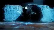 Das Bild zeigt einen gro&szlig;en blauen Stein, der zerbrochen ist, wobei helles Licht und elektrische Funken aus dem Spalt austreten.