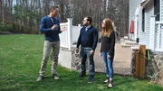 David Bromstad in a blue sweater, explains house details to the winners, by the backyard and outdoor area, one possible house