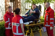 Harry (Jörg Homeyer, r.) verlädt den Patienten schon in den RTW. Nina (Sabrina Amali, 2.v.l.) sieht die Befunde von Jörg Strache (Daniel Zillmann, 2.v.r.), da fällt Ihr etwas auf. (Komparse, l.)