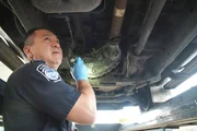 CBP-Beamter Vasquez untersucht mit einer Taschenlampe die Unterseite des Fahrzeugs eines Verd&auml;chtigen auf geschmuggelte Drogen in Pharr, Texas. (National Geographic)