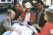 Horst Schneiders (Hannes Stelzer, li.) Tochter Sabine wird nach dem Sturz aus dem dritten Stock abtransportiert. Die Kommissare Kehler (Wolfgang Bathke, 2.v.li.) und Eschenbach (Matthias Bullach, 2.v.re.) hatten ihn benachrichtigt.