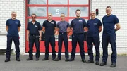 Seven firefighters in front of the vehicle depot in Fürstenwalde/Spree.