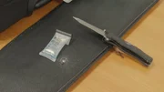 Ein Klappmesser und ein Drogenschnelltest liegen auf dem Tisch - der Fund in einer auff&auml;lligen Tasche f&uuml;hrt die Flughafenbeamten in Santiago de Chile auf eine brisante Spur.