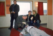 Firmenchef Bahlow (Arnold Dammann, lieg.) wurde ermordet. Gerichtsmediziner Dr. Duhler (Klaus Schindler, 2.v.li.) gibt den Kommissaren (li. Wolfgang Bathke, 2.v.re Wolfgang Krewe) und der Staatsanw&auml;ltin (Britta Schmeling) erste Hinweise auf die Todesursache.
