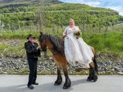 Bride Robyn posing on a horse before the wedding with horsekeeper Olaf standing next to her