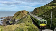 Der DART l&auml;sst die letzte Klippe hinter sich liegen: Der Nahverkehrszug zwischen Greystones und Bray f&auml;hrt auf eingleisiger Strecke. Parallel zur Bahn verl&auml;uft ein Spazierweg, der Cliff Walk.