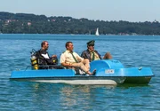 Hubert (Christian Tramitz, Mitte) und Staller (Helmfried von Lüttichau, rechts) sitzen in einem Tretboot und fahren auf den See hinaus. Yazid (Hannes Ringelstetter) sitzt hinter ihnen in Tauchermontur.