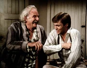 Sam Walton (Will Geer, l.) schwelgt in seinen Erinnerungen an seine Querfeldeinrennen. John-Boy (Richard Thomas, r.) hört ihm gerne zu.