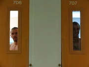 Male inmates look out their cell door windows in men's housing module