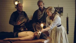 Sue (Annette Bening), die Schwester des Arztes, versorgt den schwerverletzten Button (Diego Luna). Boss Spearman (Robert Duvall, li.) und Charley Waite (Kevin Costner) sorgen sich um ihren Gef&auml;hrten.