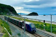 Norwegen: Eine Regionalbahn fährt am Trondheimfjord entlang und nähert sich dem Bahnhof Hell.