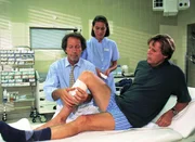 Dr. Ulrich Waldner (Hartmut Becker, l.) versorgt die Schusswunde von Dr. Stefan Frank (Sigmar Solbach). Eine Krankenschwester (Komparsin) assistiert.