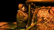 Deckhand Nick Mavar, secures pots on the stack with ties at night.