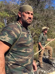 L-R: EJ Snyder und Jeff Zausch halten Speere am Fluss.