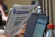 Die letzte Zeitung - Regionaljournalismus auf dem Prüfstand. Gedruckte Zeitung "Südostschweiz" neben einem Notebook.