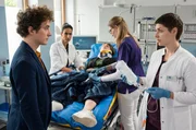 Die Architektin Britta Stadler (Nicole Marischka, M.) wurde bei einem Arbeitsunfall schwer verletzt. Ihr Kollege Ole Ritter (David Hugo Schmitz, l.) ist &auml;u&szlig;erst besorgt und weicht nicht von ihrer Seite. Dr. Leyla Sherbaz (Sanam Afrashteh, 2.v.l.) und Dr. Theresa Koshka (Katharina Nesytowa, r. mit Komparsin, 2.v.r.) fordern ihn auf, die Notaufnahme zu verlassen.