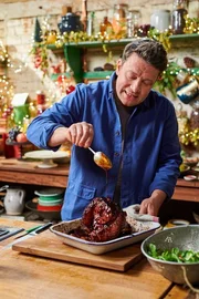 Jamie Oliver betr&auml;ufelt seinen Schinken mit einer Sauce.