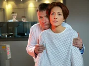 Pia Heilmann (Hendrikje Fitz, rechts) hat die Nachuntersuchung bezüglich ihrer Brustkrebserkrankung. Ihr Mann Dr. Roland Heilmann (Thomas Rühmann) hat jedoch keine guten Nachrichten: Pia hat eine Metastase an der Wirbelsäule. Der Kampf gegen den Krebs beginnt von Neuem.
