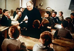 Der Lausebengel Ludwig (Hansi Kraus, 6. von rechts) spielt dem fr&ouml;mmelnden Religionslehrer Falkenberg (Rudolf Rhomberg, Mitte), genannt "Kindlein", einen derben Streich.