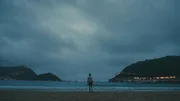 Ein Junge in einem Fu&szlig;balltrikot steht auf einem Ball am Meer.