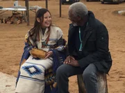 SHIPROCK, N.M. - On the last day of the Navajo Kinaalda ceremony, Kinaalda girl "Changing Woman" Maysun Peterson holds a piece of the sacred corn cake in her hands and shares a laugh with Morgan Freeman.